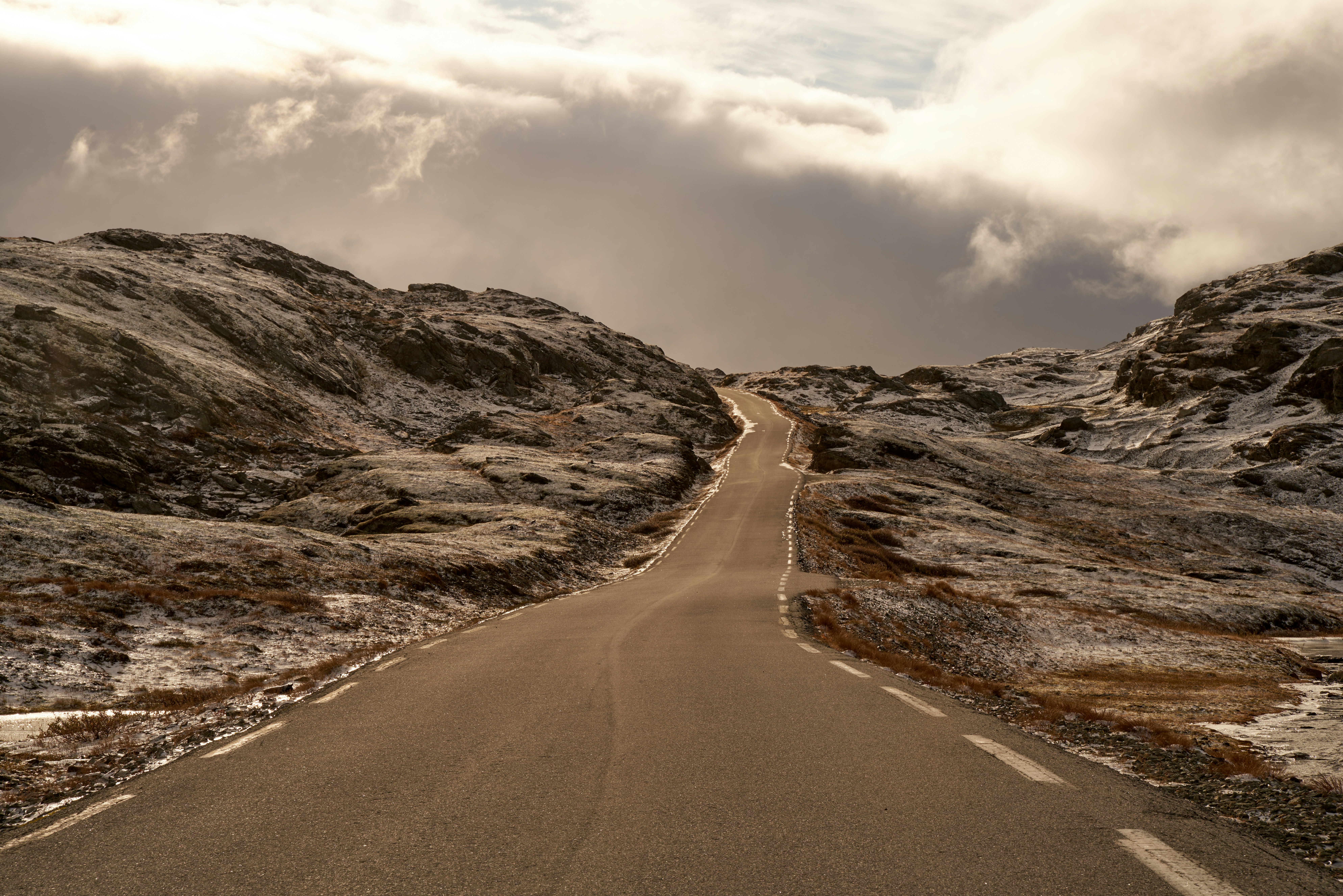 an empty road in the middle of a mountain range
