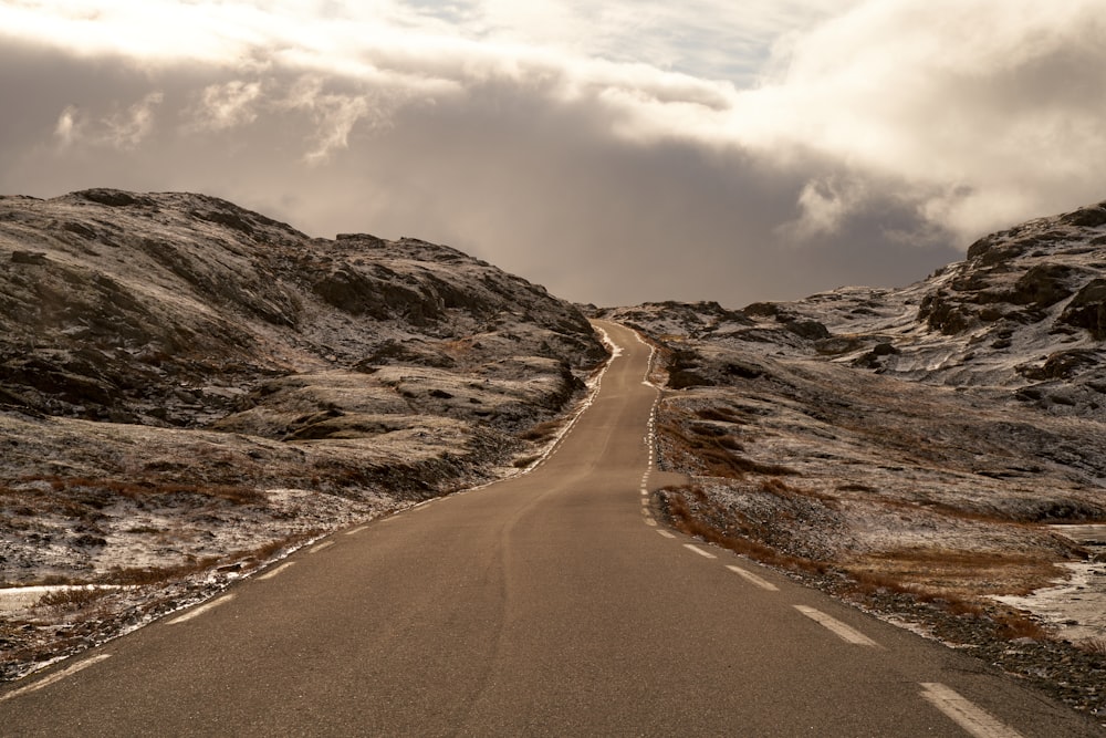 an empty road in the middle of a mountain range