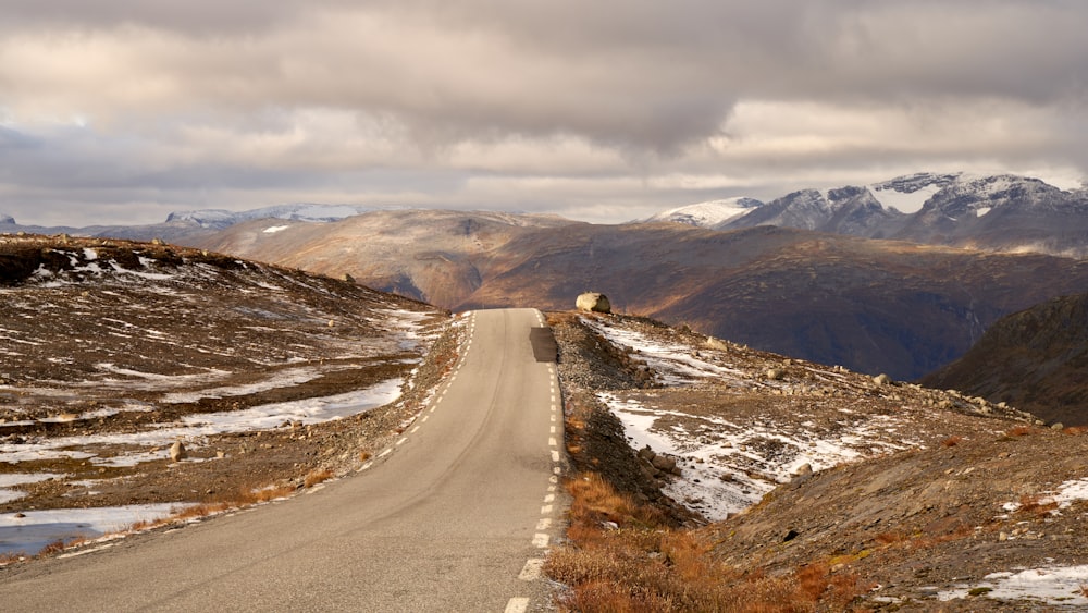 an empty road in the middle of a mountain range