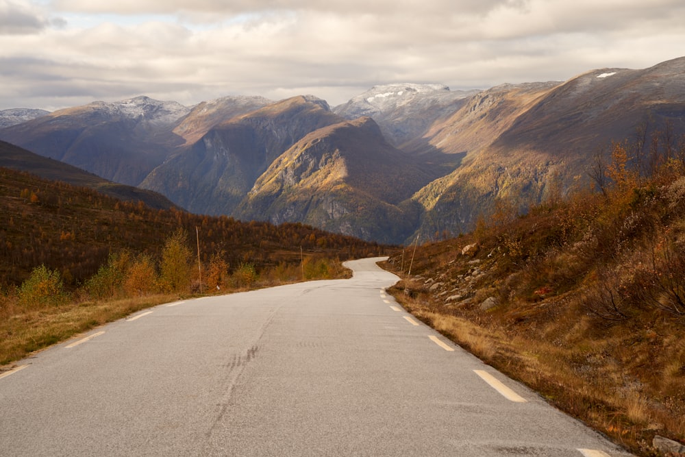 an empty road with mountains in the background