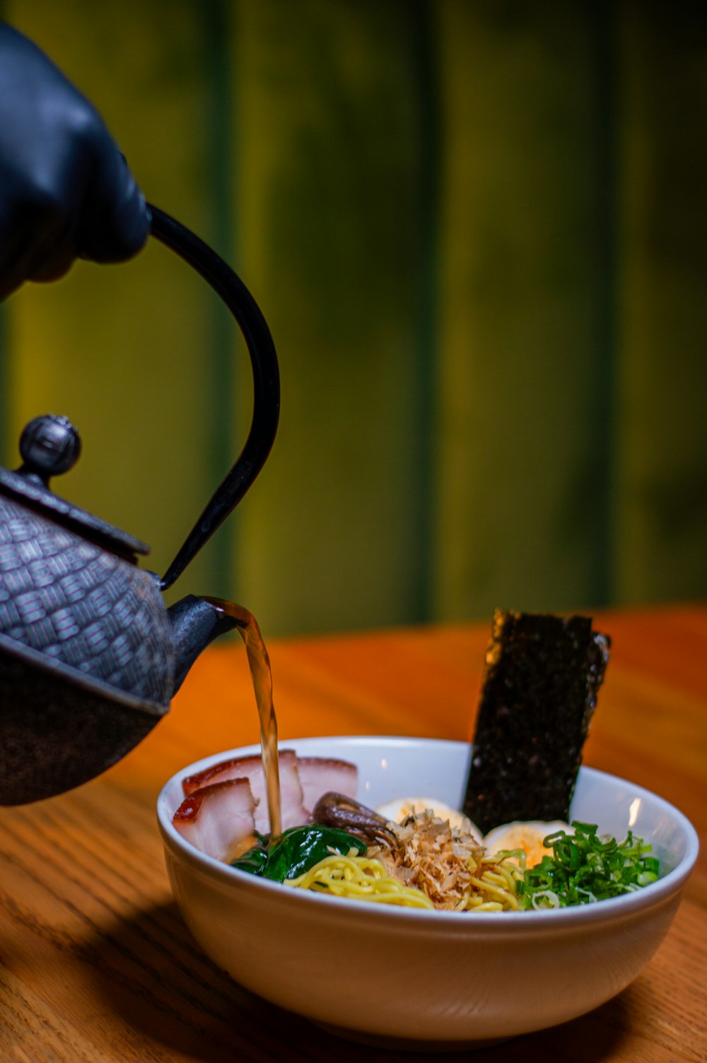 a tea pot pouring tea into a bowl of food