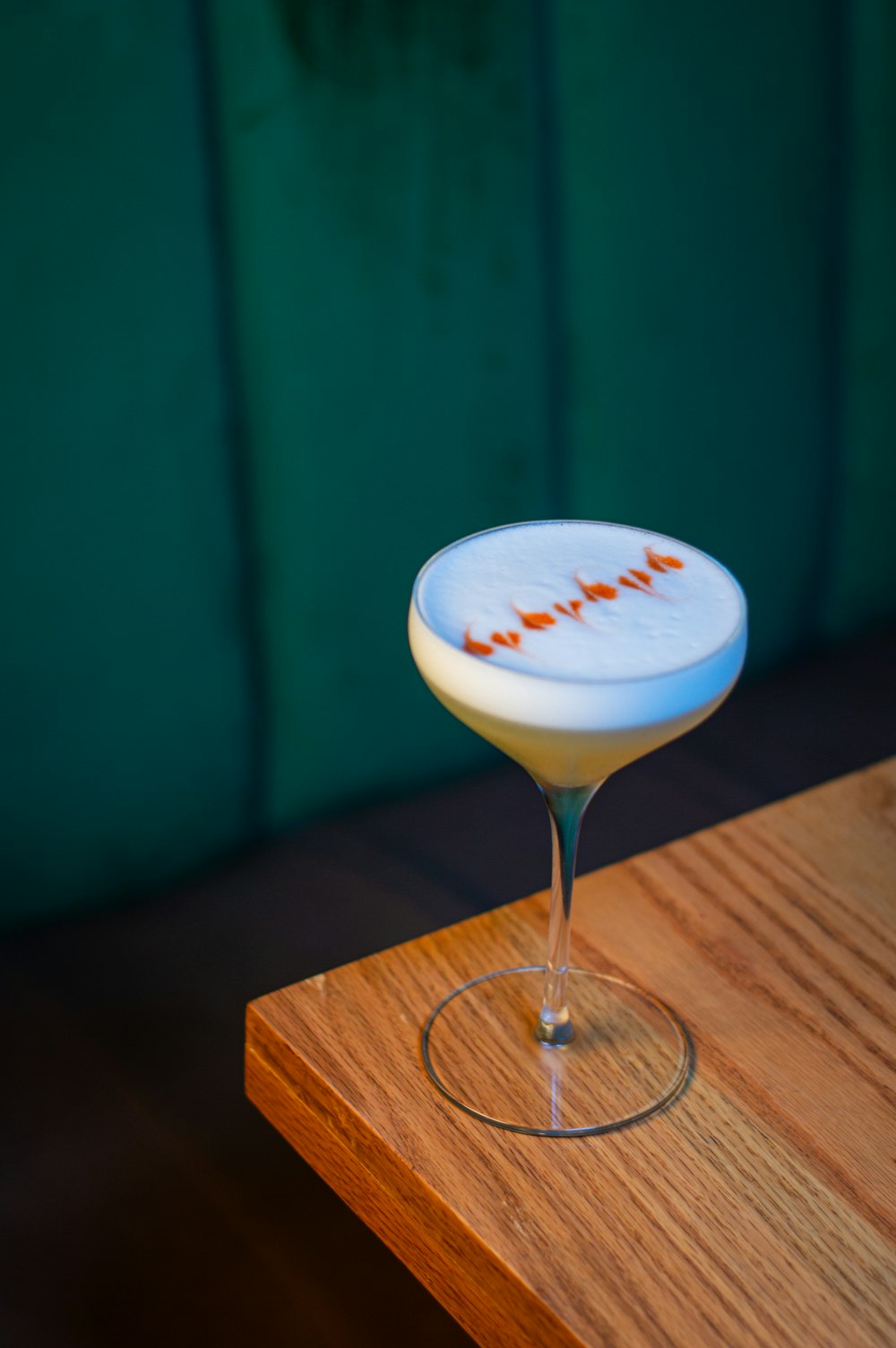 a white cocktail sitting on top of a wooden table