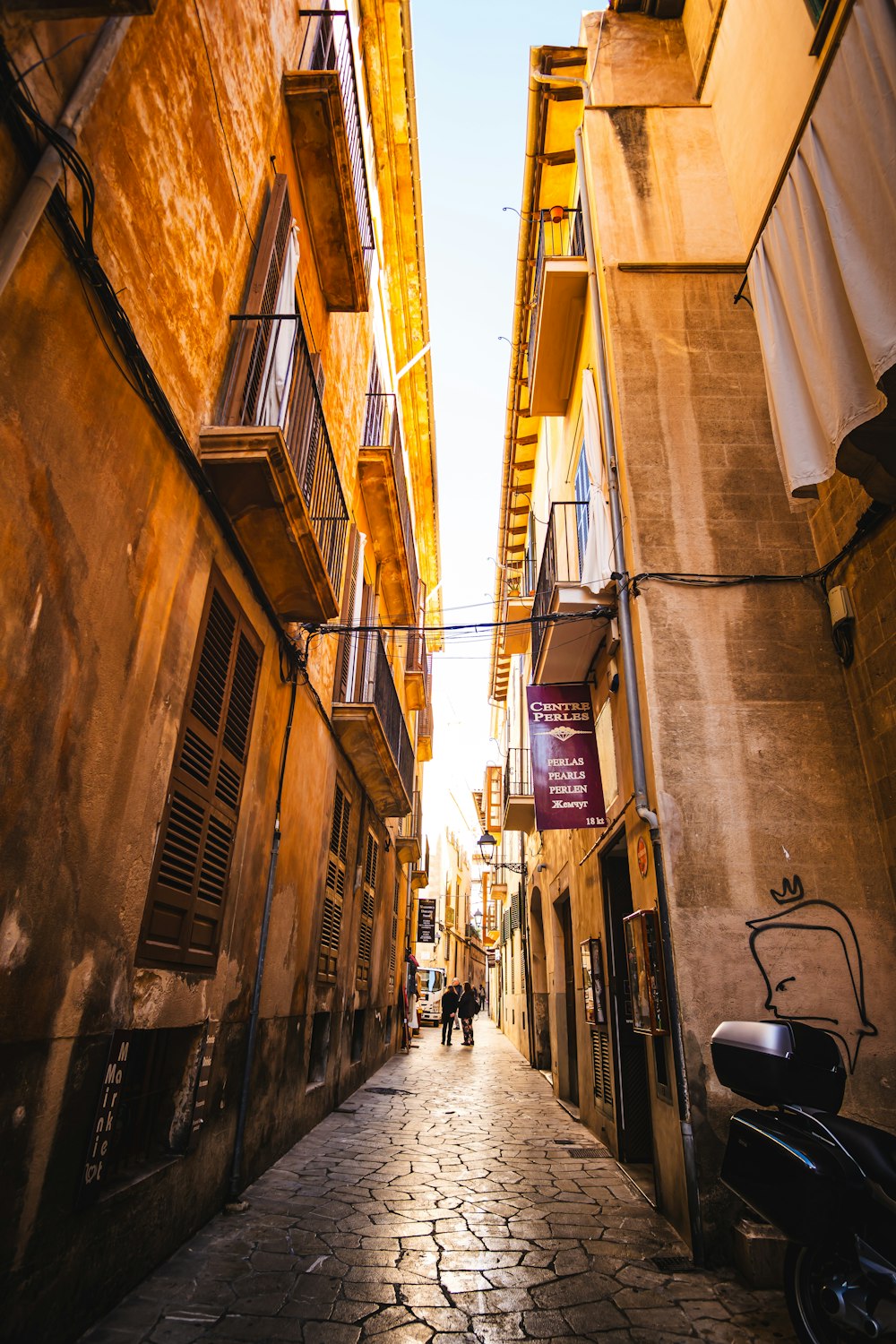 two people walking down an alley way between two buildings