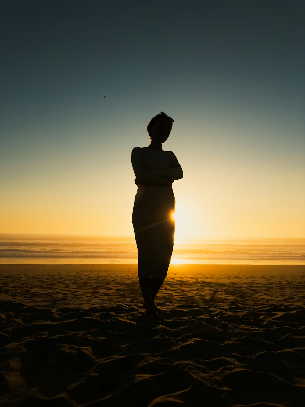 une femme debout au sommet d’une plage de sable