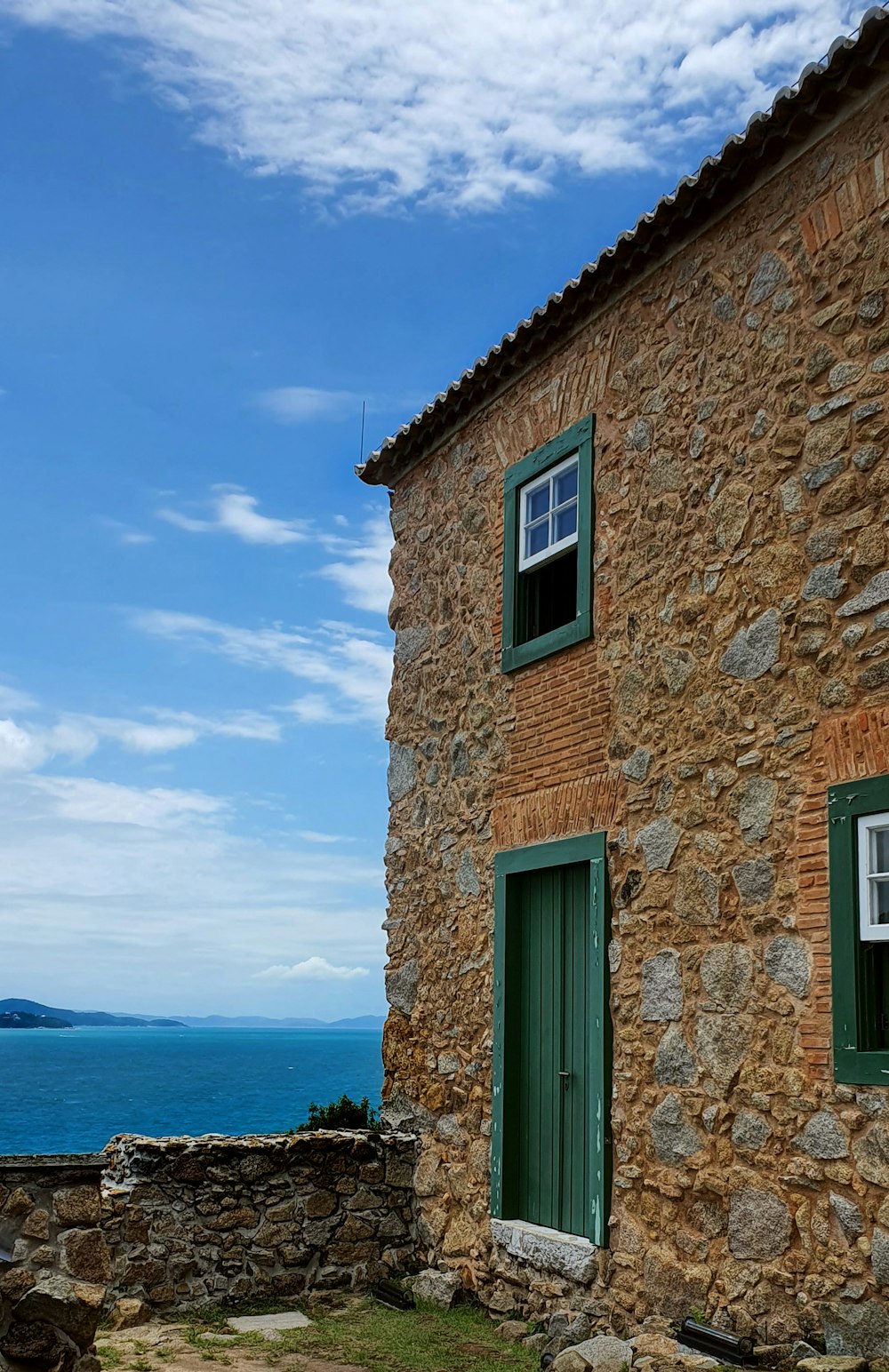 a stone building with a green door and window