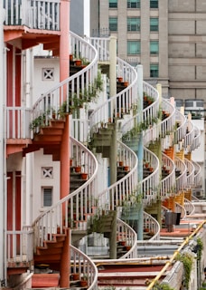 a row of buildings with a bunch of plants growing on the balconies