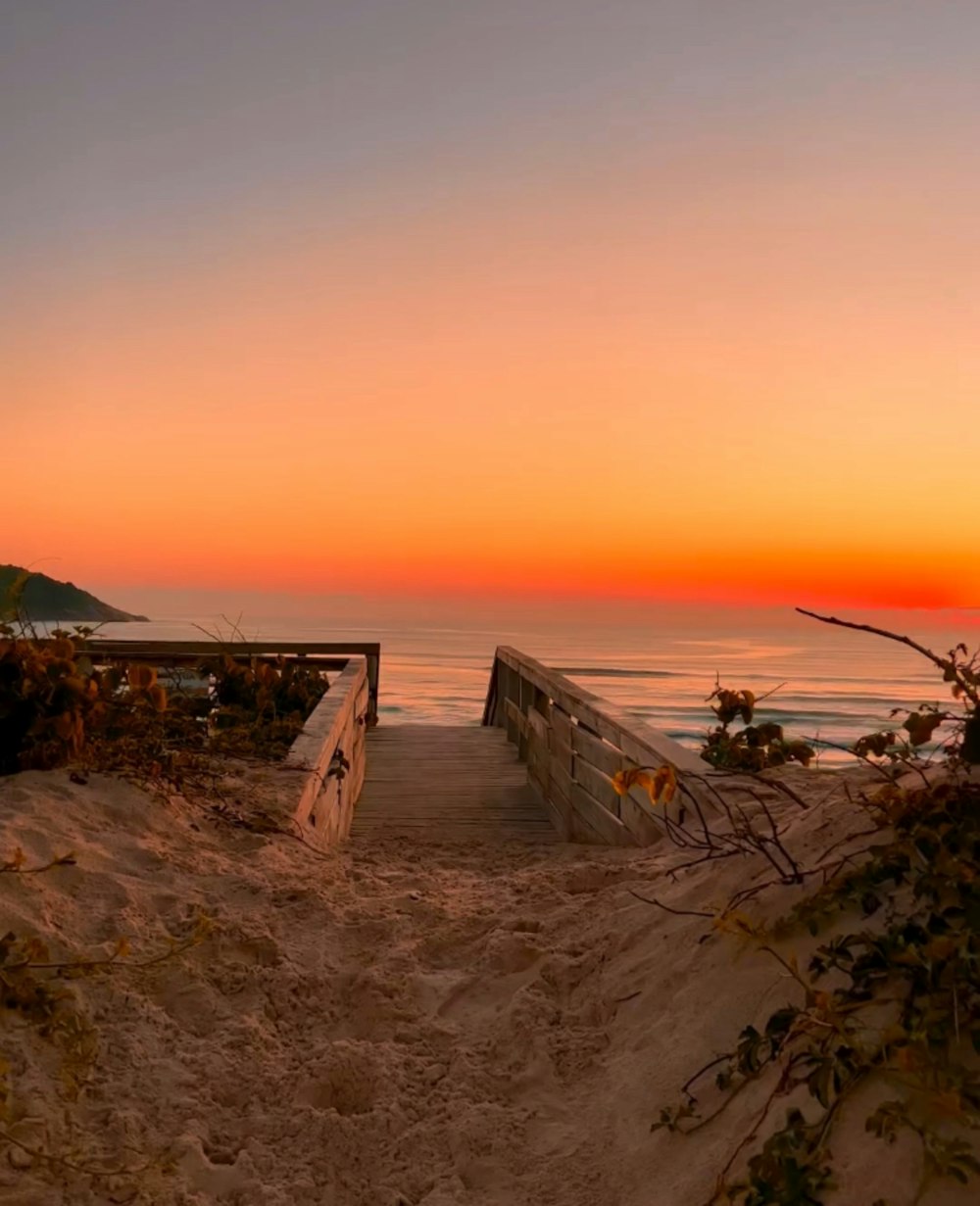 a wooden bench sitting on top of a sandy beach