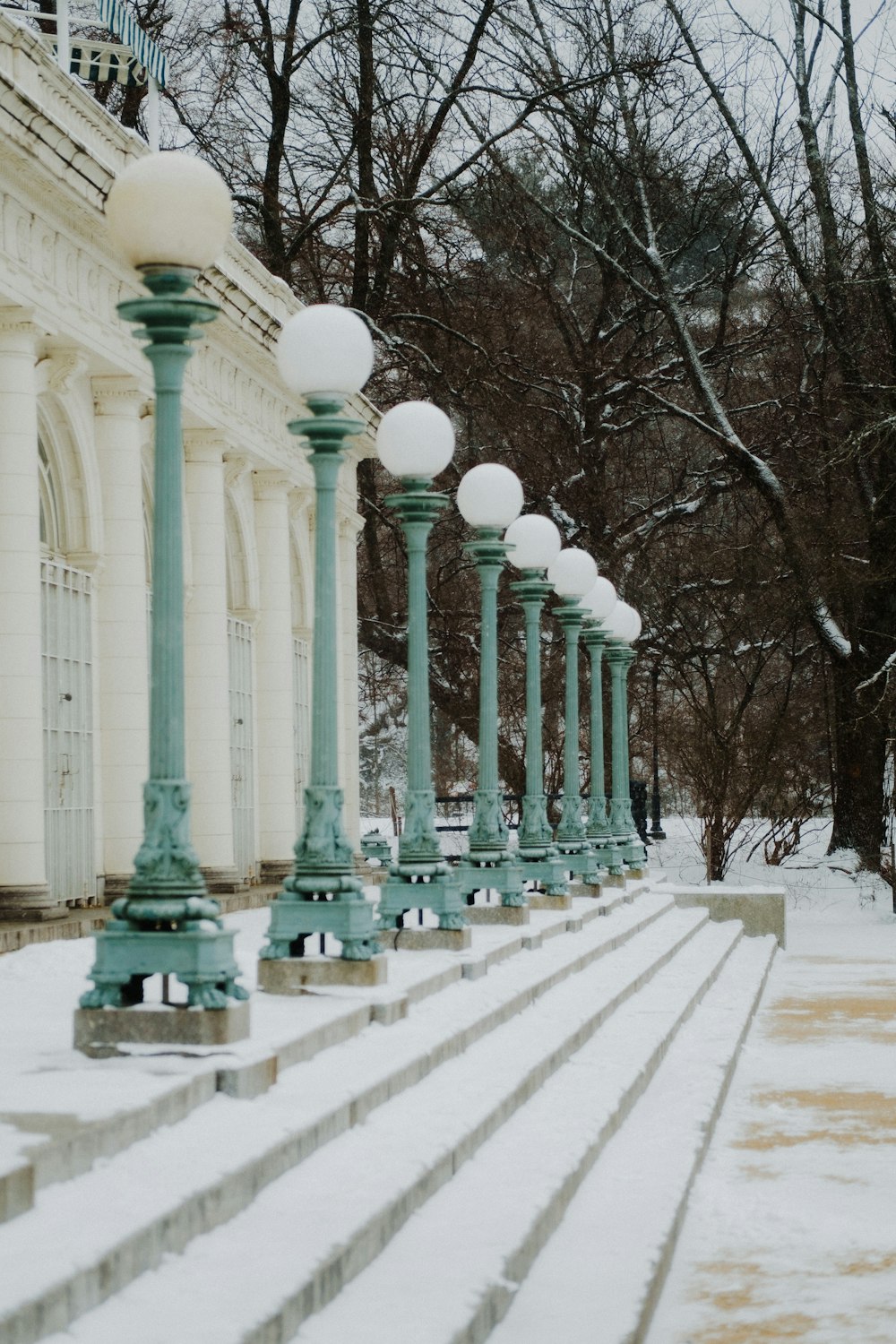 a row of green and white street lights in the snow