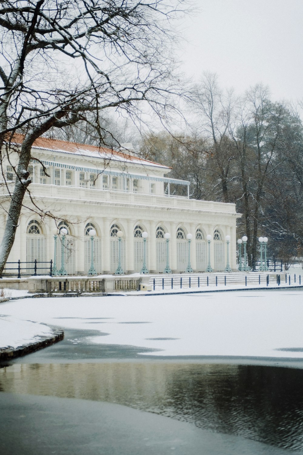 a white building with a red roof and a pond in front of it