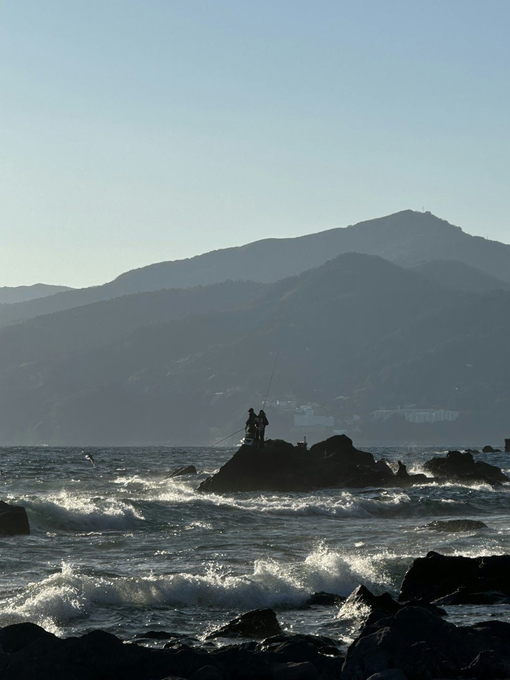 a man fishing on a rock in the ocean