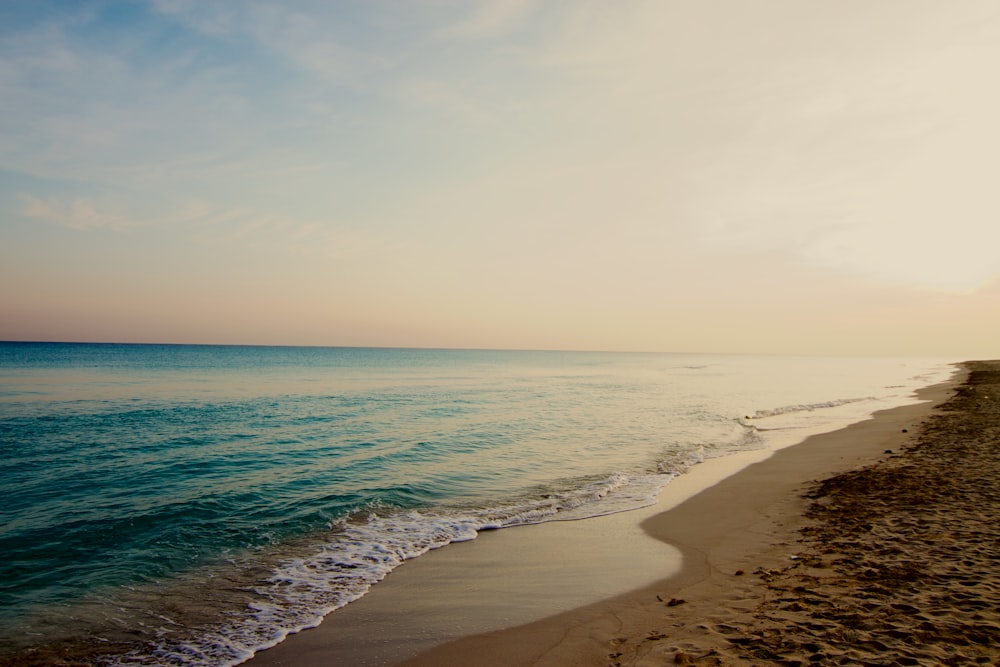 a sandy beach with waves coming in to the shore