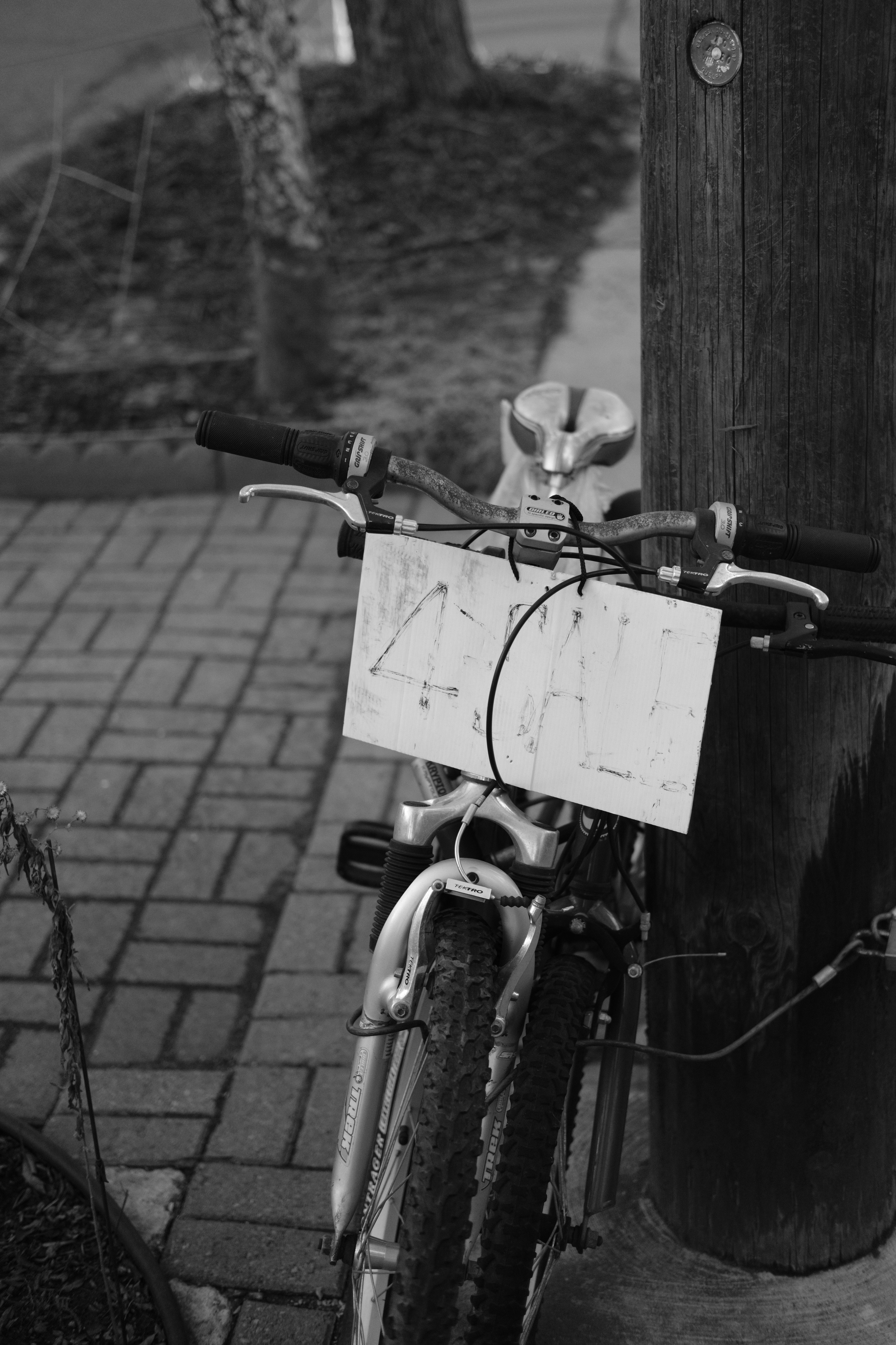 a bicycle parked next to a pole on a sidewalk
