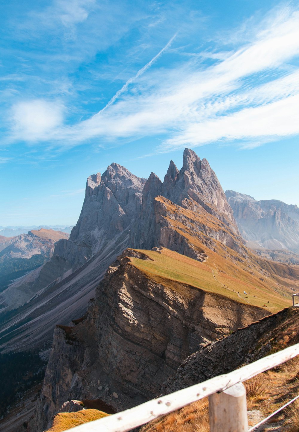 a man standing on top of a mountain next to a lush green hillside