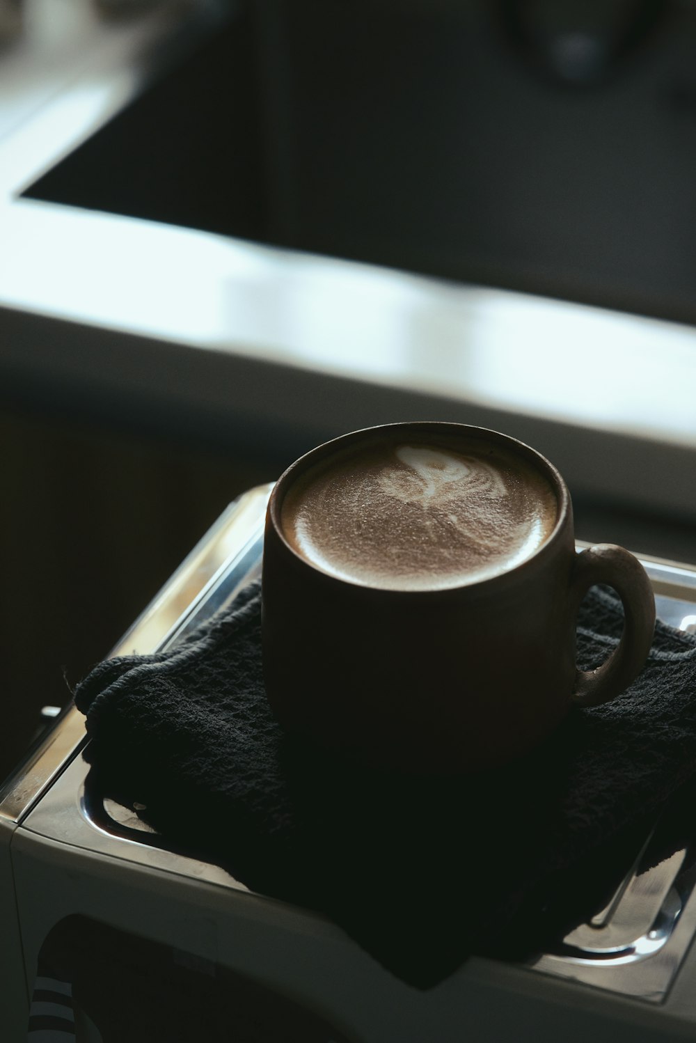 a cup of coffee sitting on top of a microwave