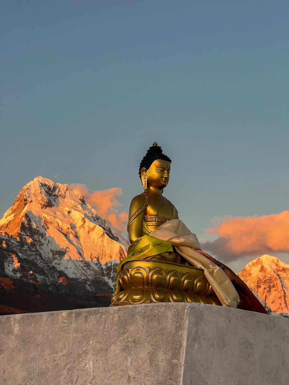 a golden buddha statue sitting in front of a mountain