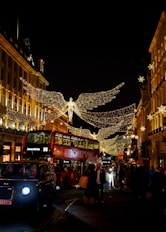 a city street with a double decker bus and christmas lights