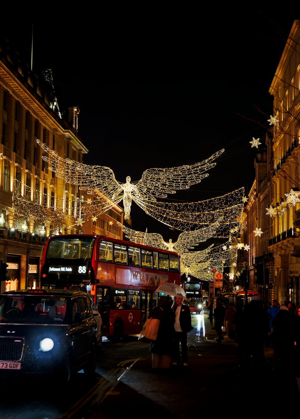 a city street with a double decker bus and christmas lights