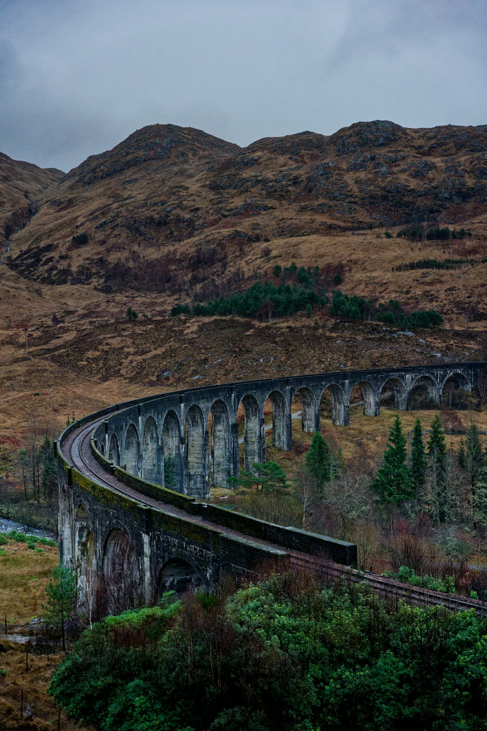 a train traveling over a bridge in the mountains