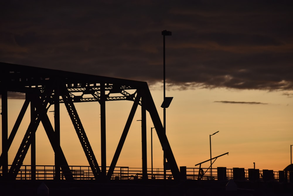 the silhouette of a bridge against a cloudy sky