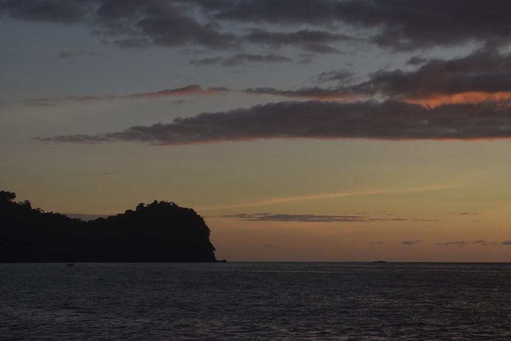 the sun is setting over a small island in the ocean