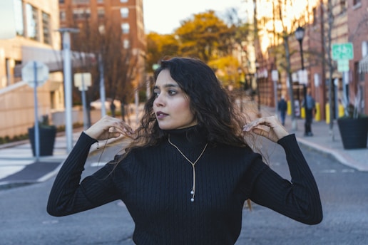 a woman standing on a street corner holding her hair