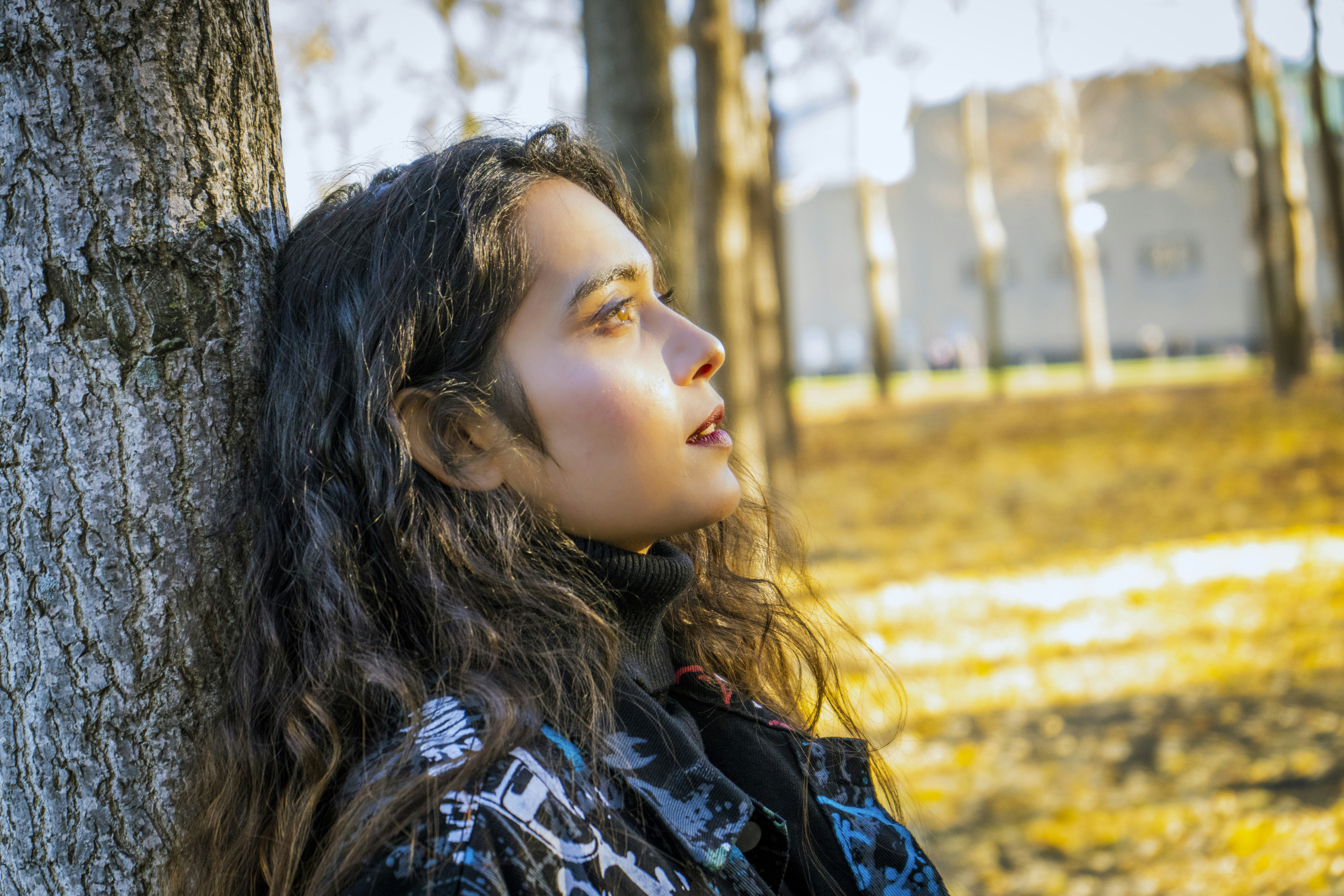 a woman leaning against a tree in a park