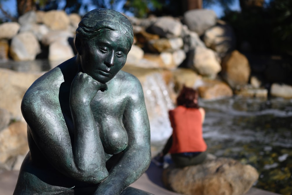 a statue of a woman sitting on a rock