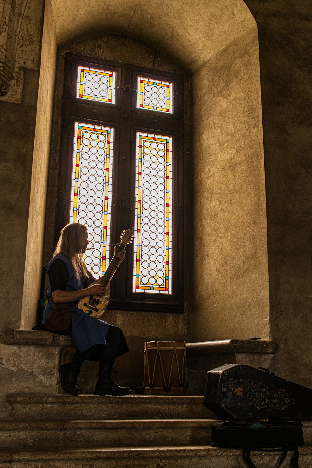 a woman sitting on a set of stairs playing a guitar
