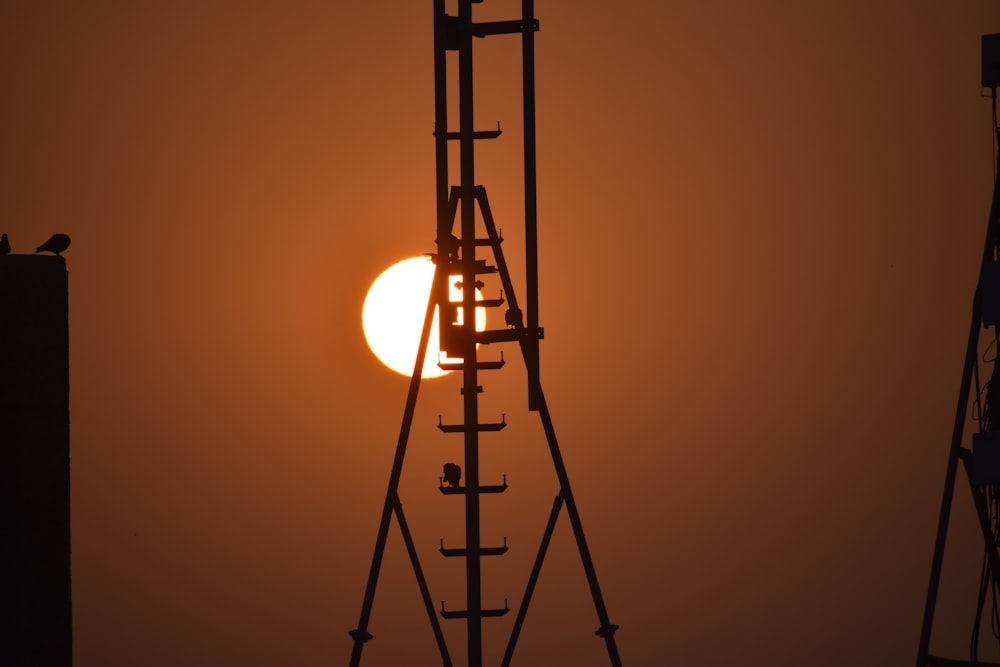 the sun is setting behind a tall tower