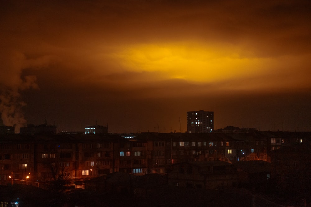 a city at night with smoke coming out of the stacks