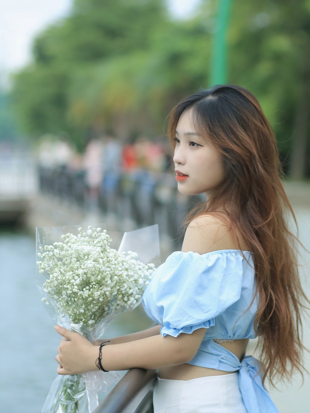 a woman holding a bouquet of flowers next to a body of water