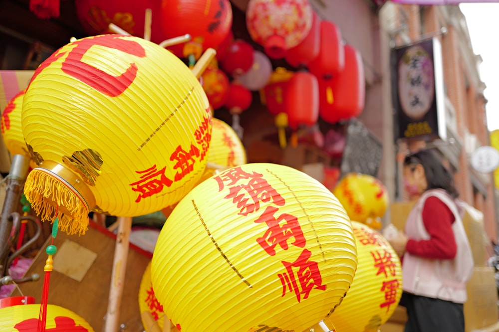 yellow lanterns with chinese writing on them in a street