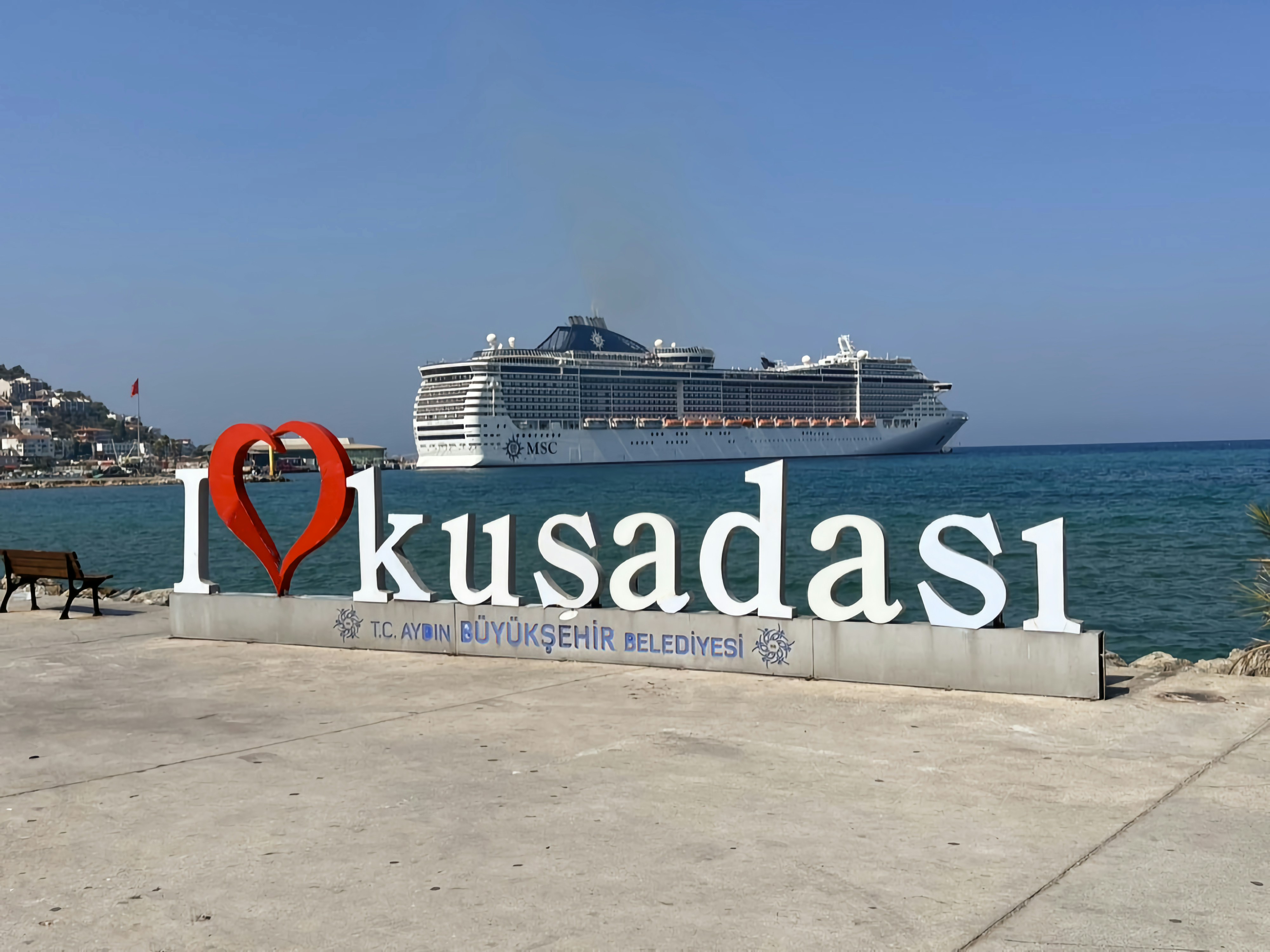 a large cruise ship in the background with a sign in the foreground