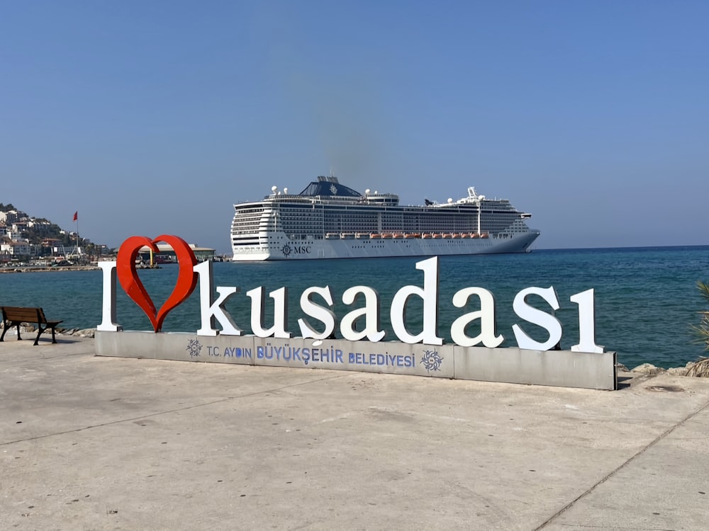 a large cruise ship in the background with a sign in the foreground