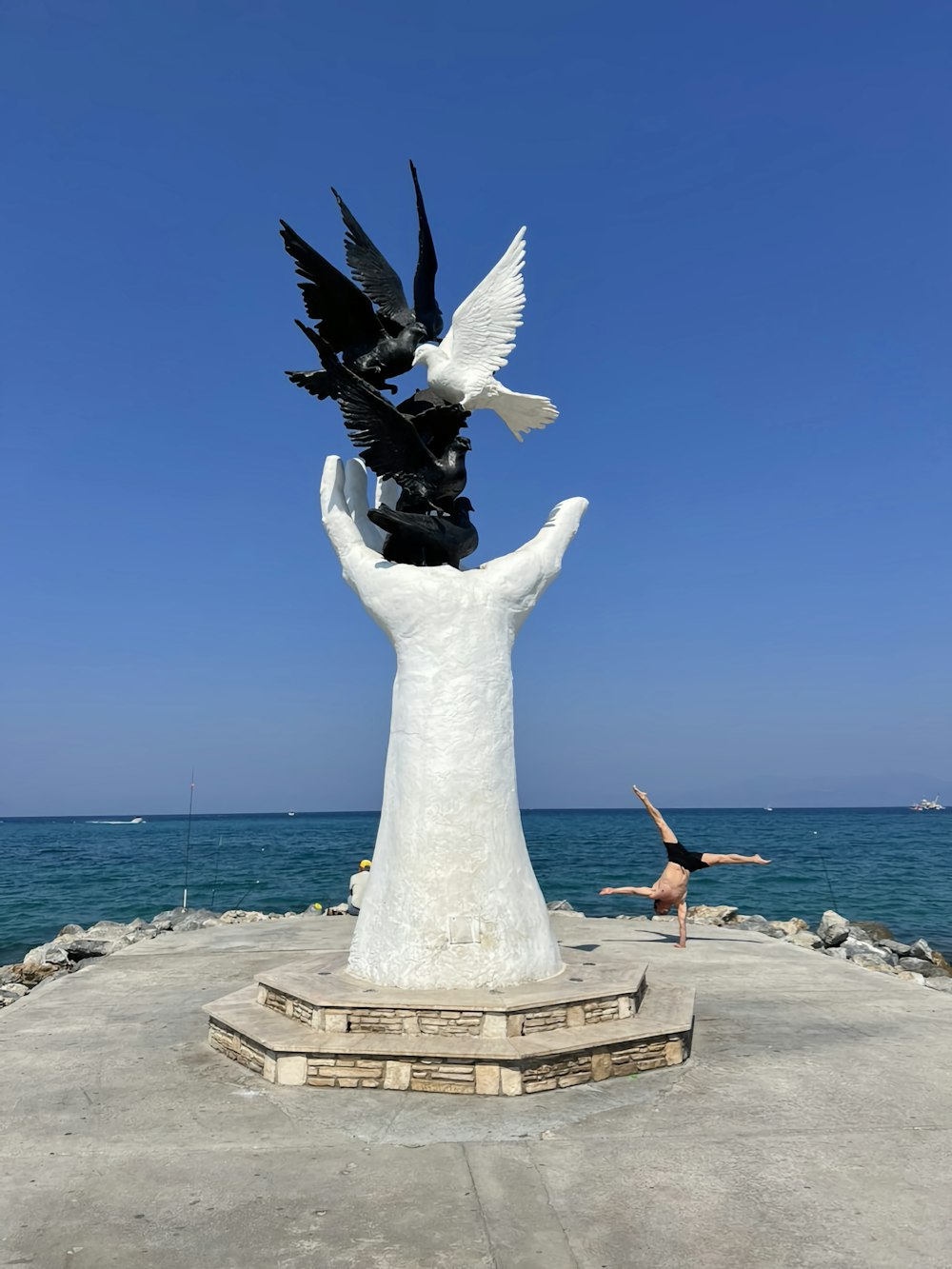 a woman standing next to a statue of a hand holding two birds