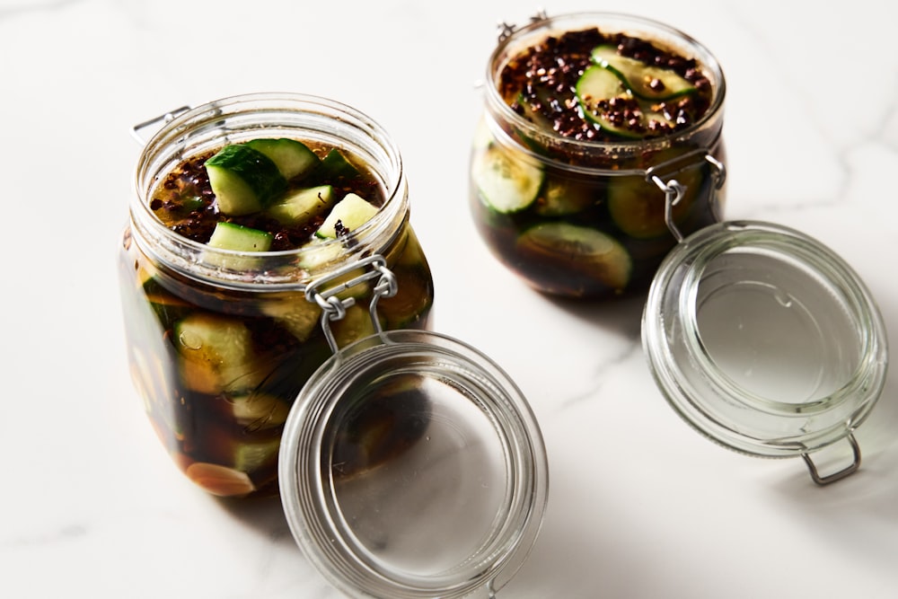 a couple of jars filled with pickles on top of a table