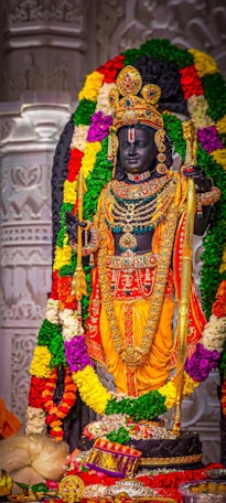 a statue of a hindu god surrounded by flowers