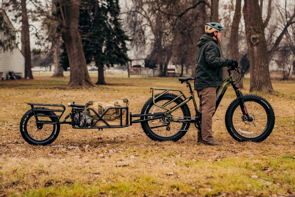 a man standing next to a bike in a field