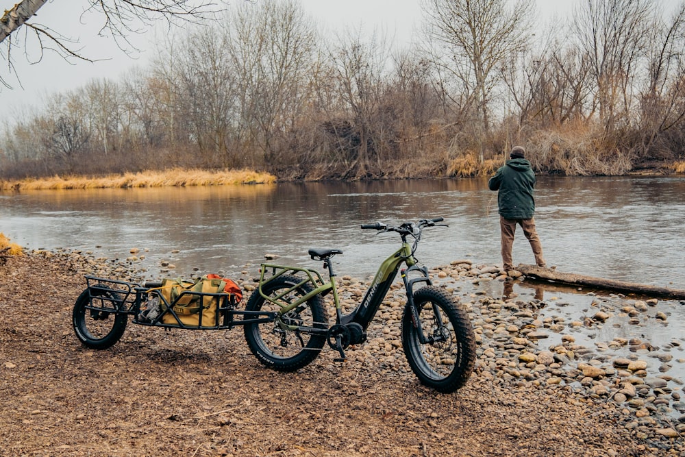a man standing next to a bike near a river
