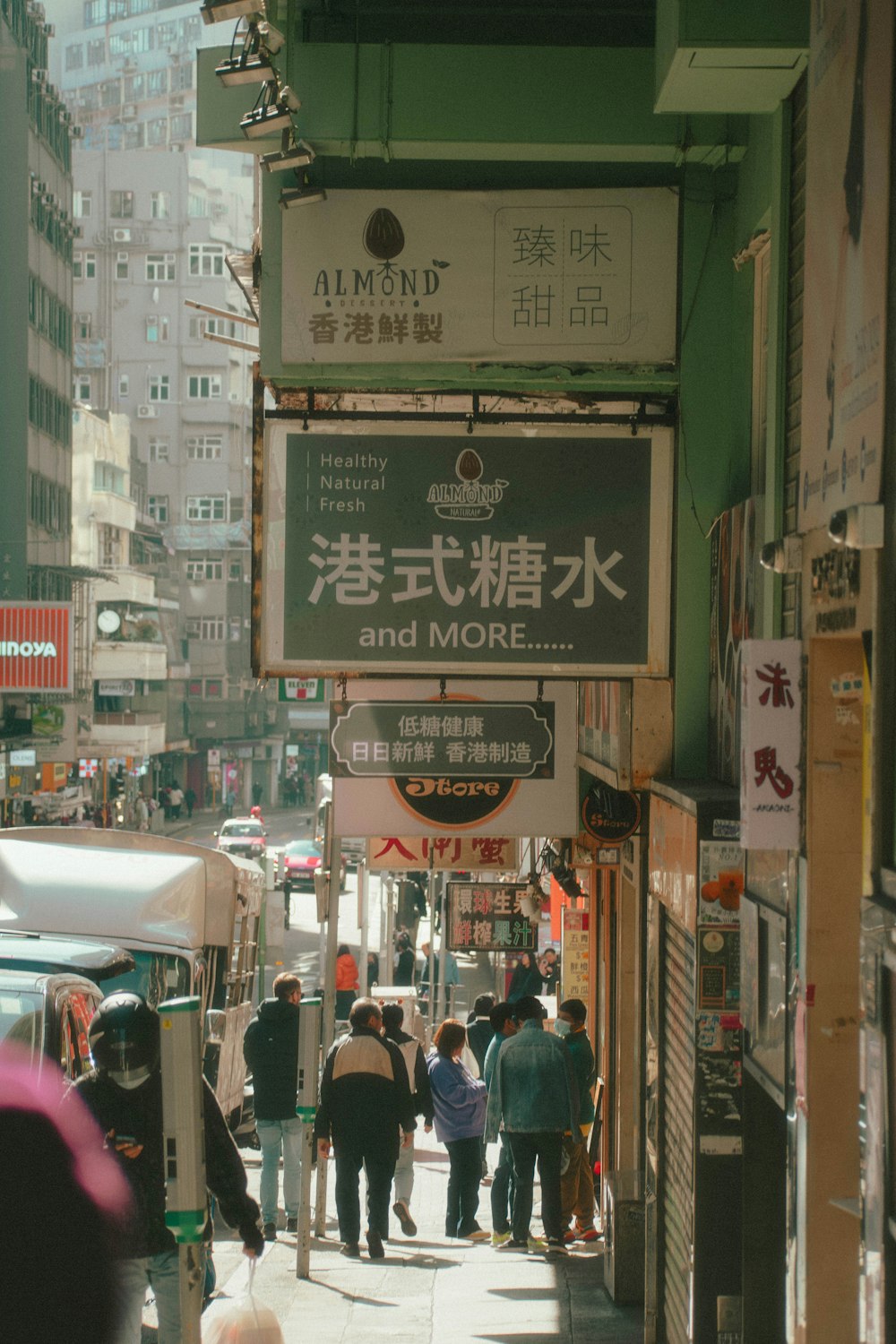 a group of people walking down a street next to tall buildings