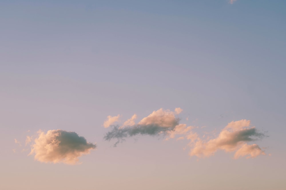 a plane flying in the sky with a few clouds