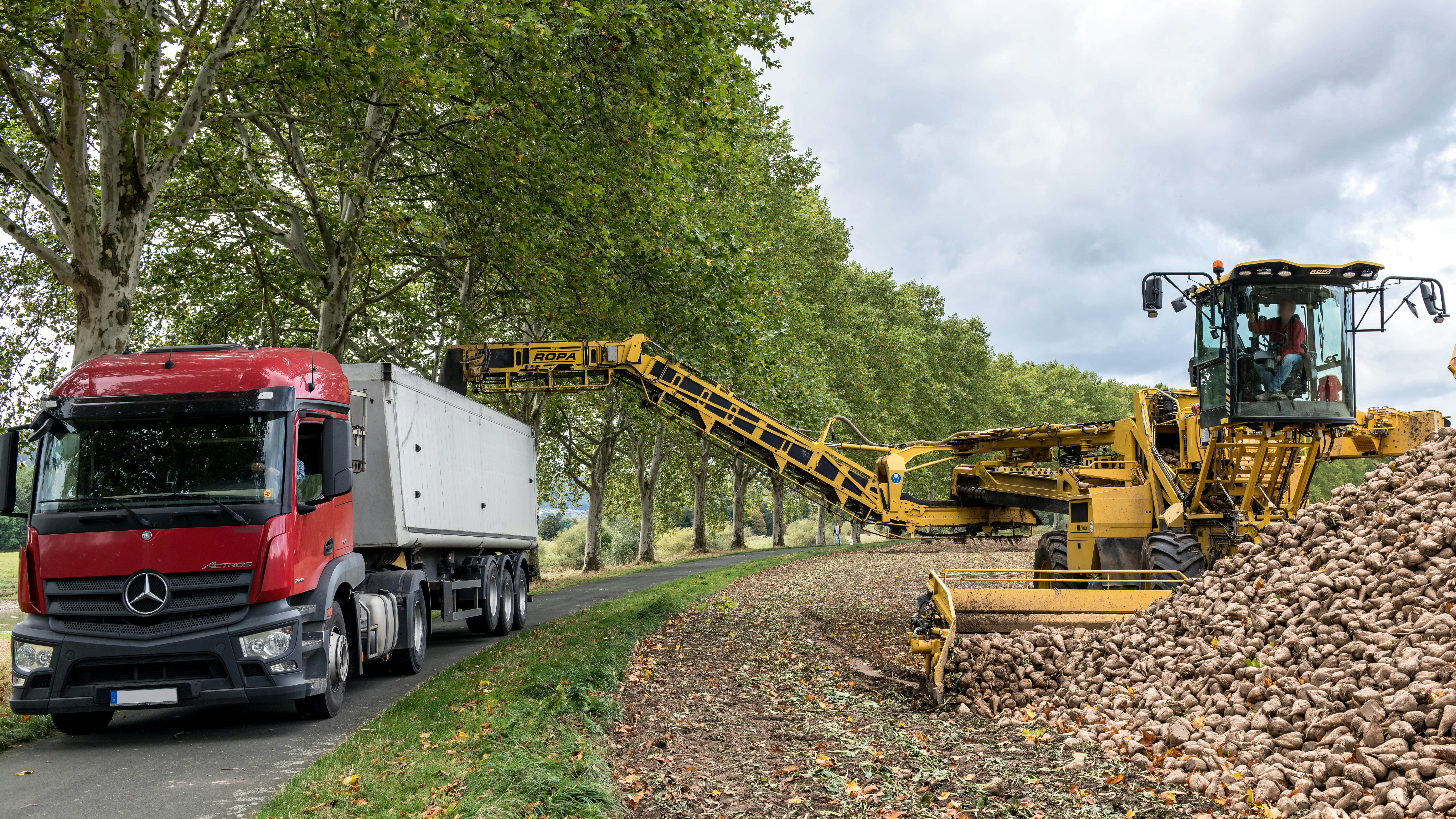 a red truck driving down a road next to a pile of dirt