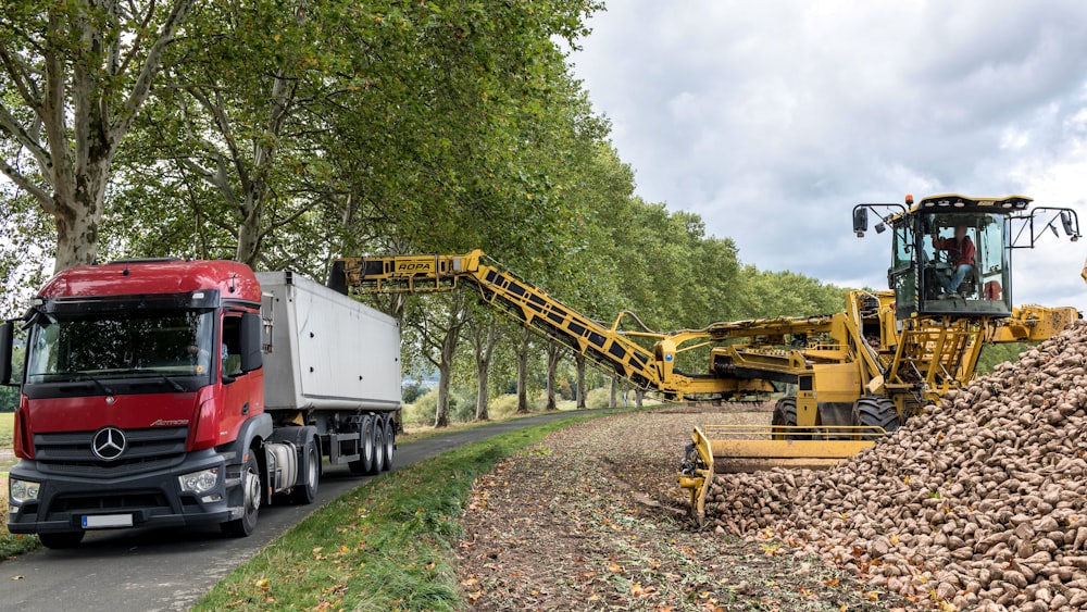 a red truck driving down a road next to a pile of dirt