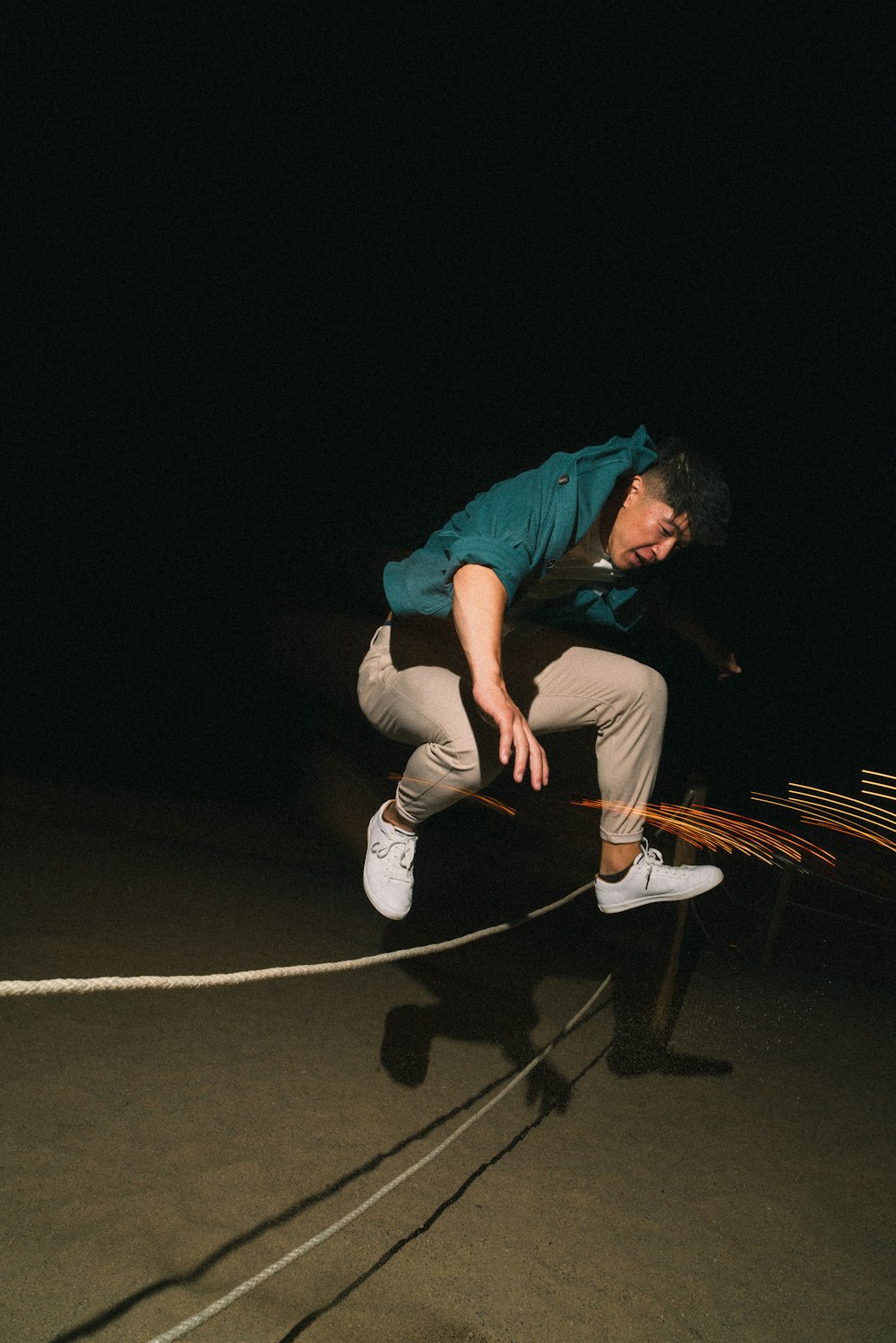 スケートボードの上でロープを飛び越える男
