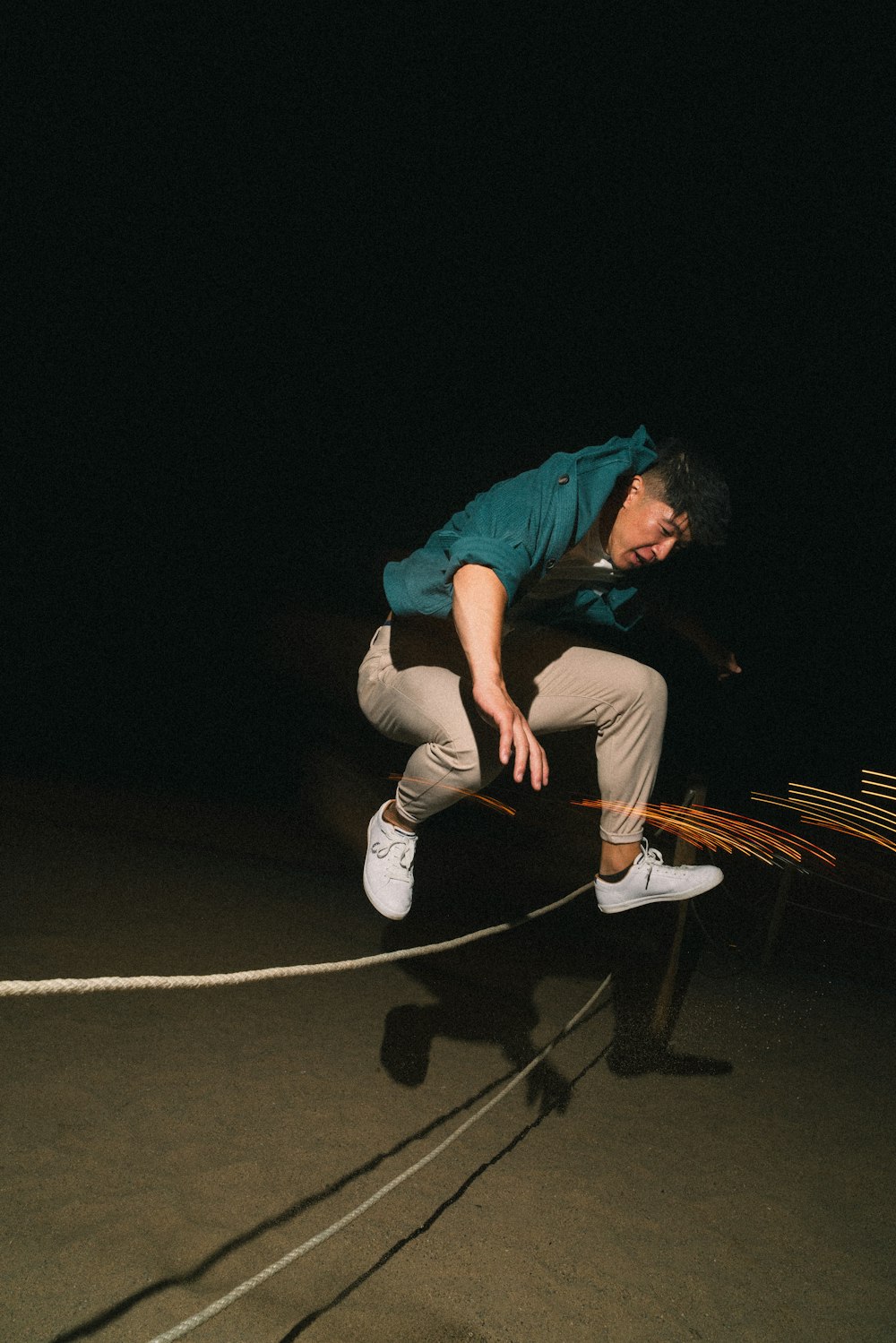 a man jumping over a rope on top of a skateboard