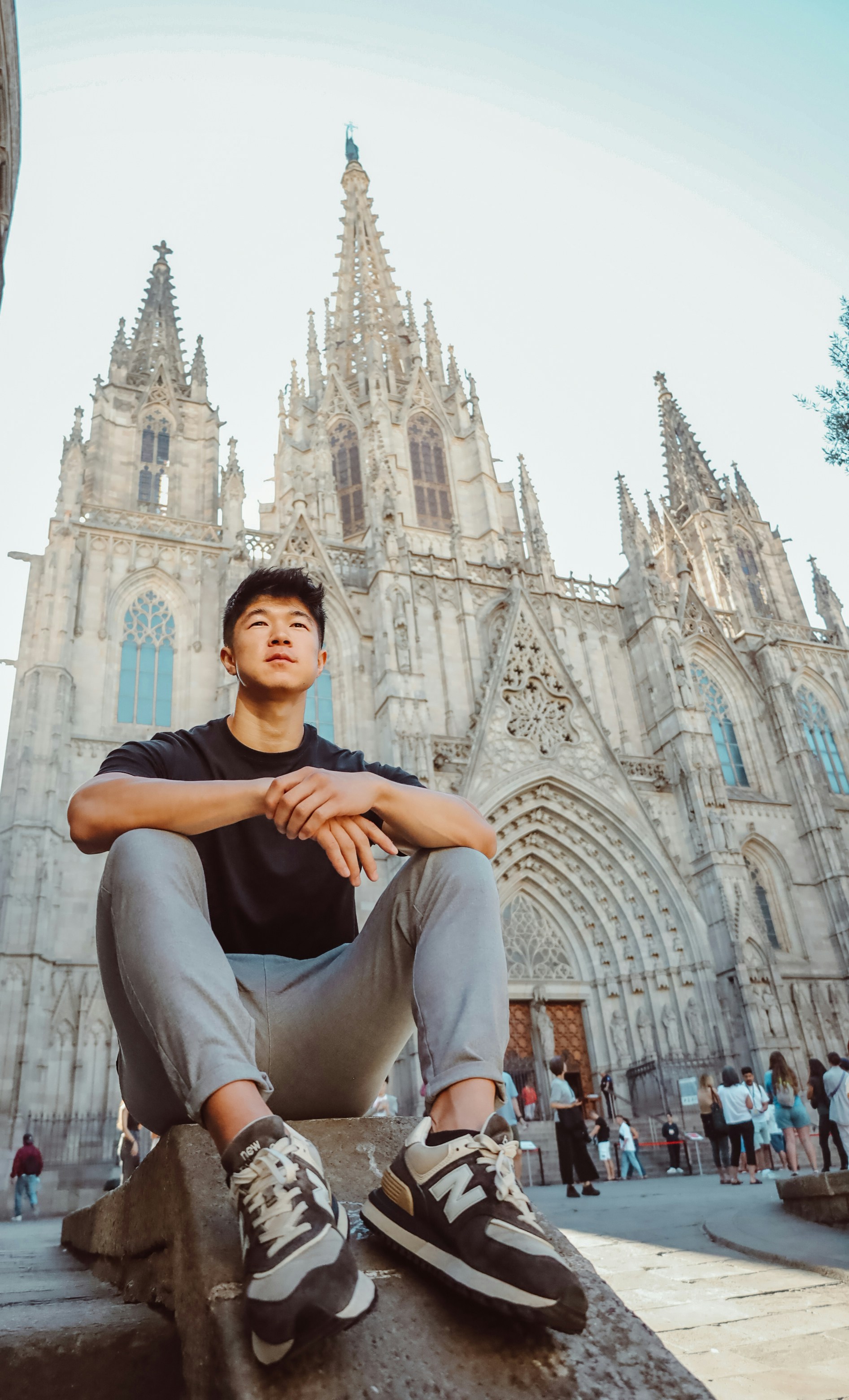 um homem sentado em uma saliência em frente a uma catedral