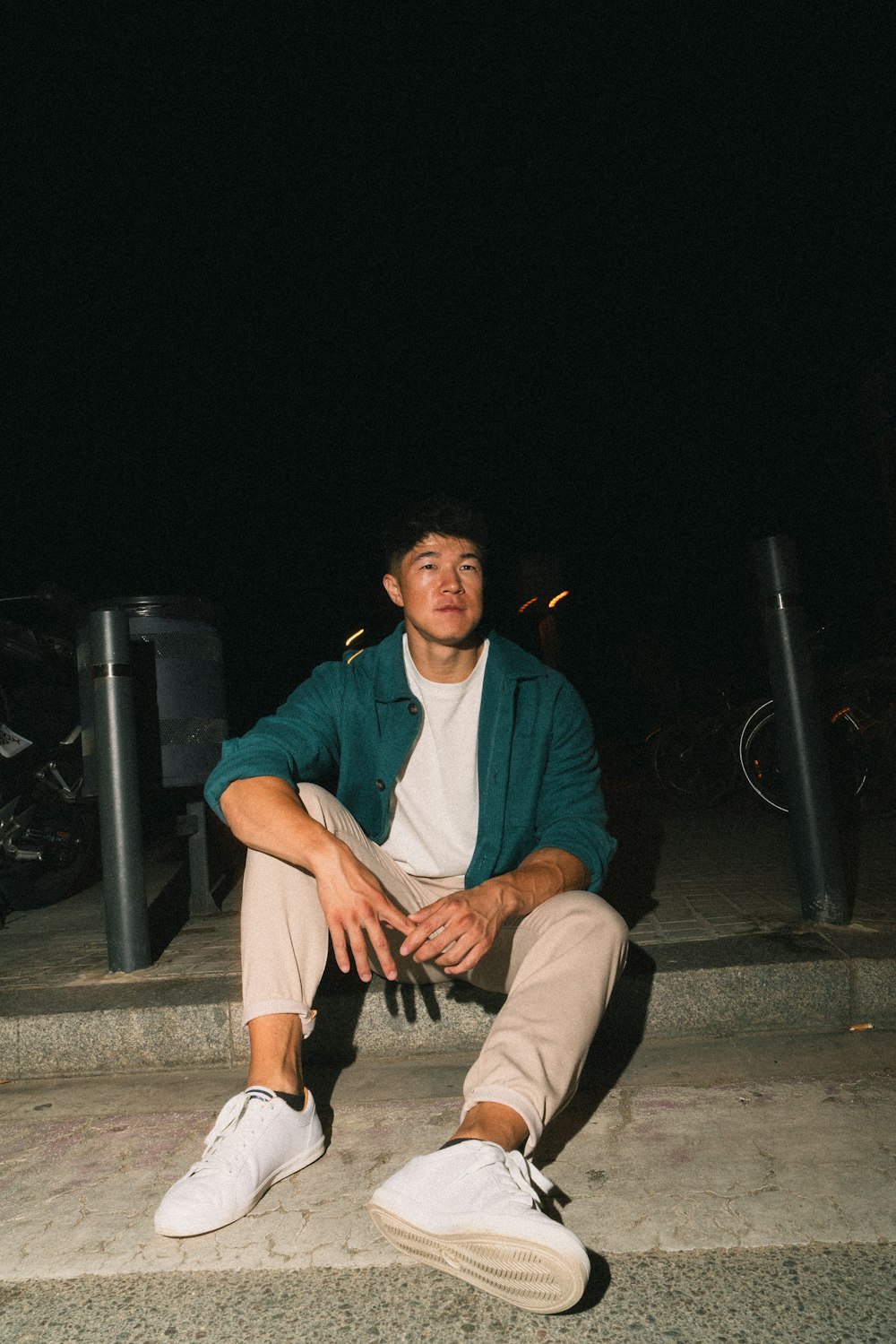 a young man sitting on steps at night