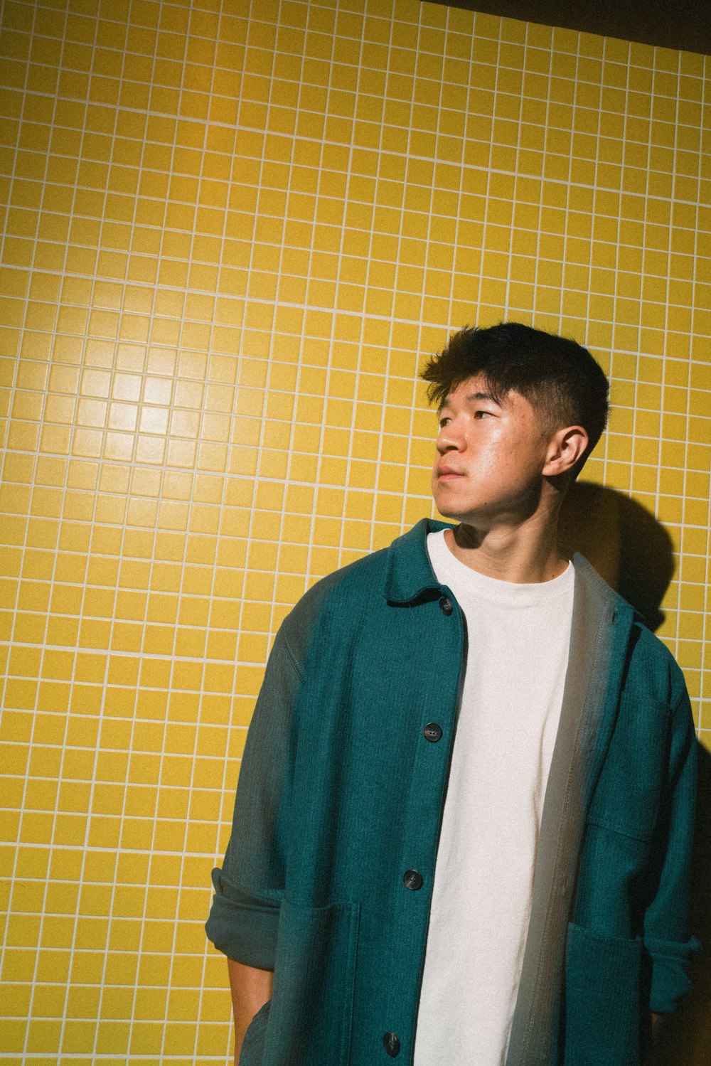 a man standing in front of a yellow tiled wall