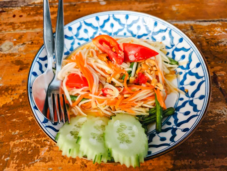 a blue and white plate topped with a salad and a fork