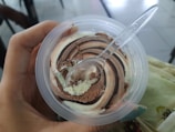 a person holding a plastic container with ice cream in it